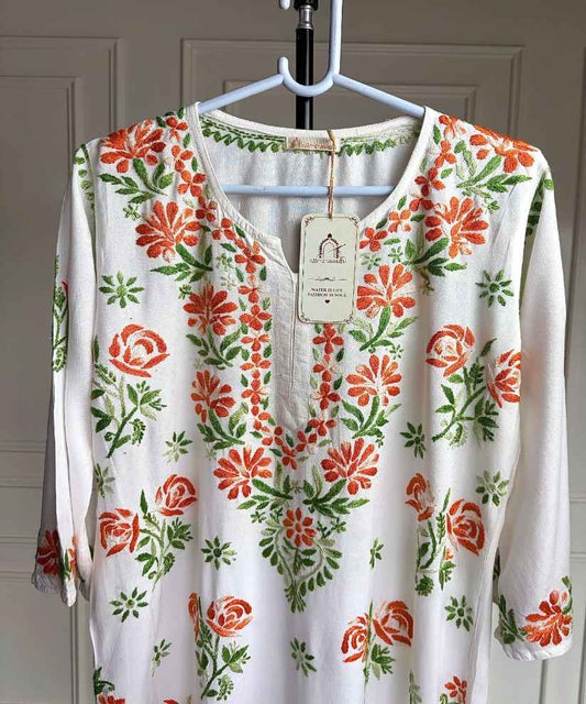 Close-up of shaded orange and green hand Chikankari embroidery on neckline and upper body of Mehram white rayon kurti — Noor-e-Awadh